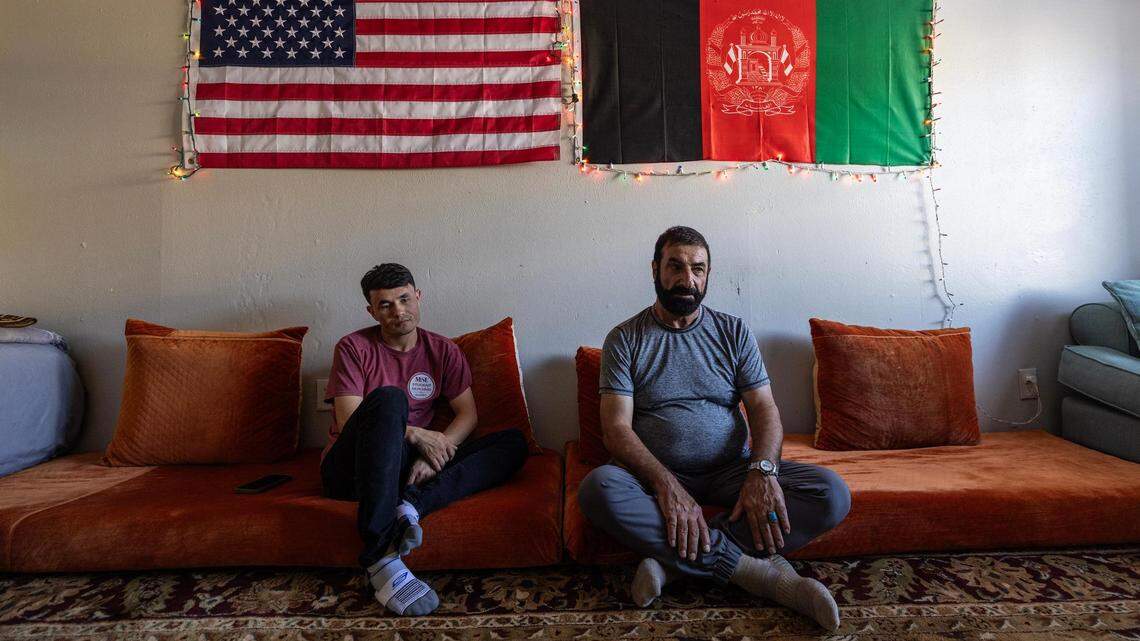 Mohammad Wasiq, left, and Mohammad Amini, Afghan refugees who fled Afghanistan following the Taliban takeover, sit together and enjoy milk tea under the American and Afghan flags in Amini’s apartment living room in Fort Worth on Sept. 27.