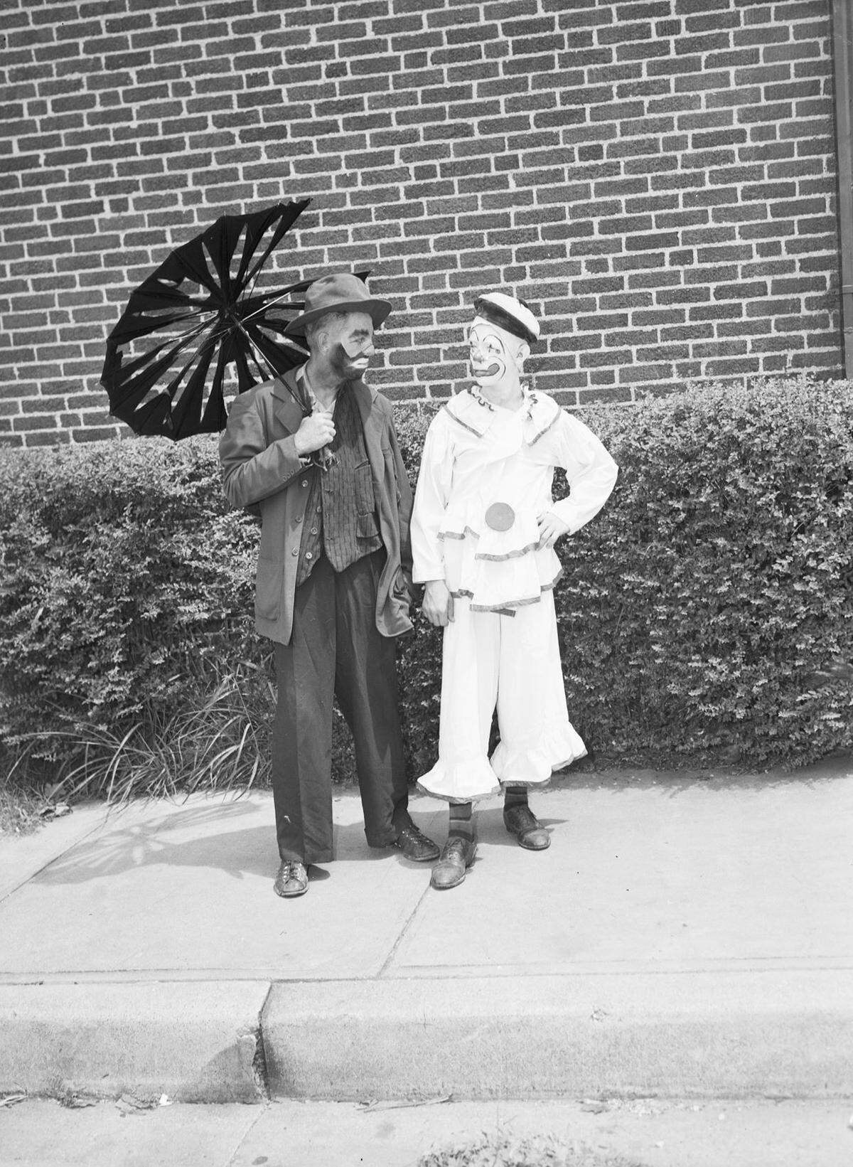 Mr. Cameron is holding a broken umbrella. Both men have face paint and are wearing their circus clown costumes.