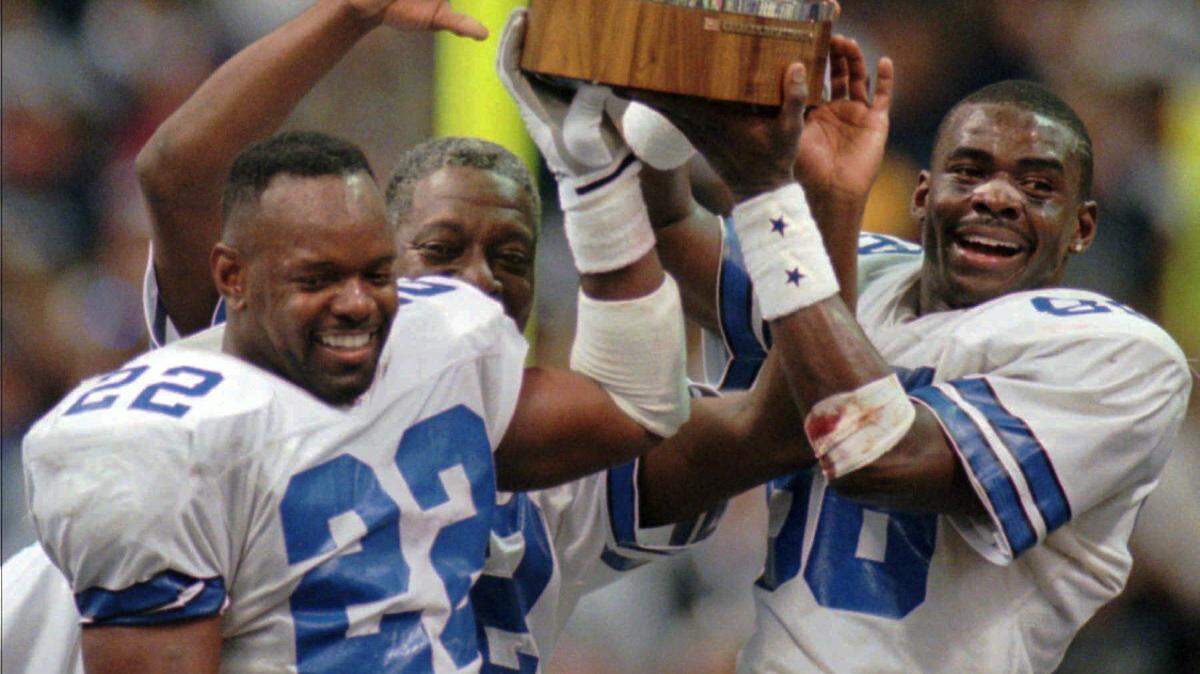 Dallas Cowboys’ Emmitt Smith (22) and Michael Irvin, right, hold up the NFC Championship trophy after the Cowboys defeated the Green Bay Packers 38-27 in Irving.
