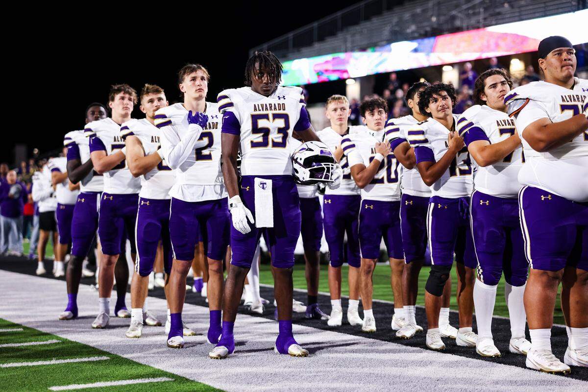 Alvarado players line up with their hand over their hearts for the national anthem before their Class 4A Division I area playoff game against Sulphur Springs on Friday, Nov. 21, 2025, at Children’s Health Stadium in Prosper, Texas.