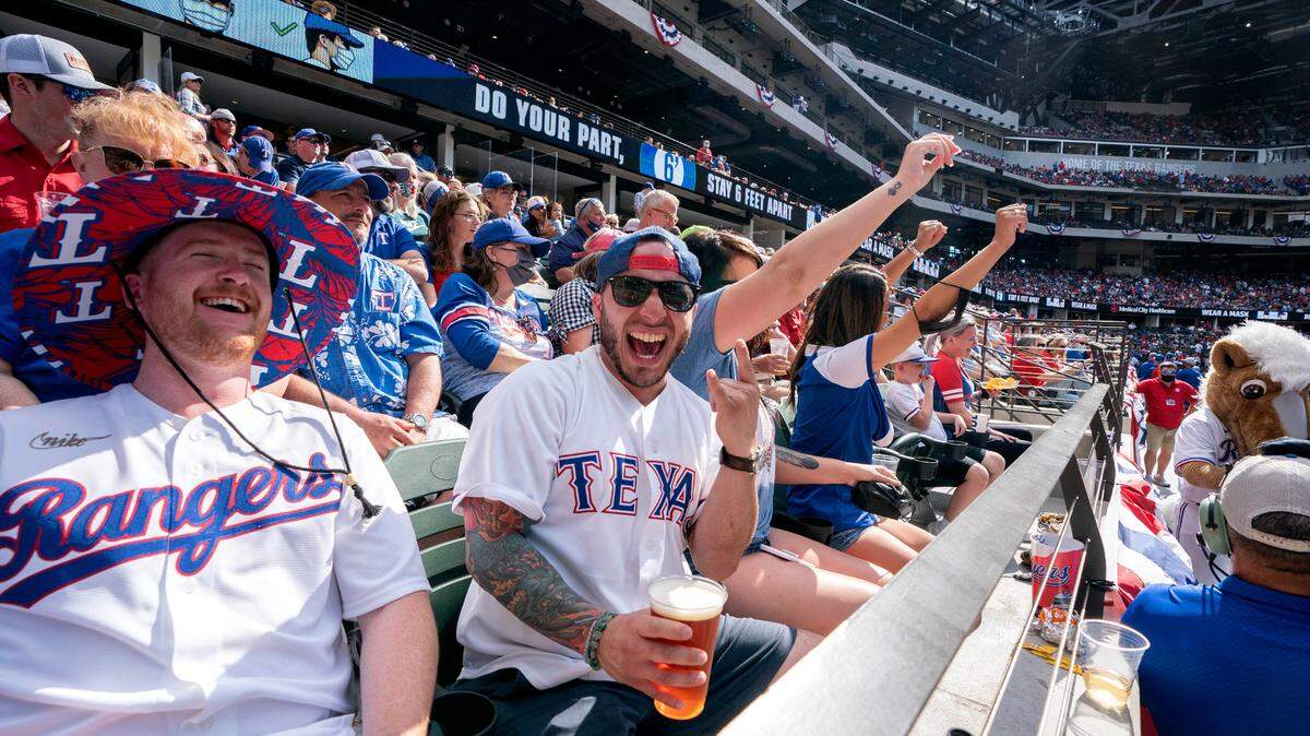 Texas Rangers fans Cameron Leverett, left, and Anthony Sosa celebrate during the fourth inning of a baseball game against the Toronto Blue Jays Monday, April 5, 2021, in Arlington, Texas. (AP Photo/Jeffrey McWhorter)