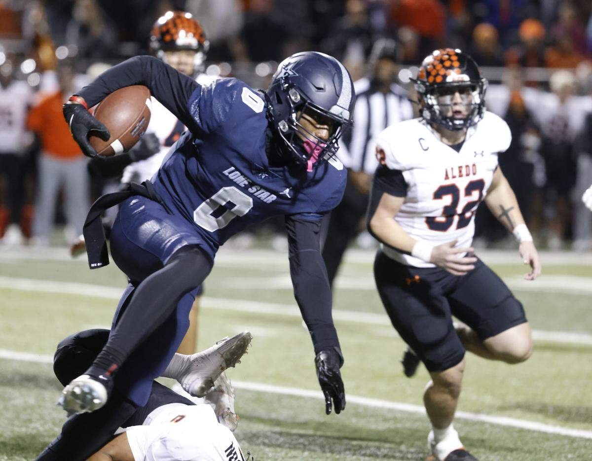 Frisco Lone Star running back Davian Groce (0) jumps over an Aledo defender during the first half of a UIL Class 5A Division I Semifinal on Friday Dec. 12, 2025 at Vernon Newsom Stadium in Mansfield, Texas.