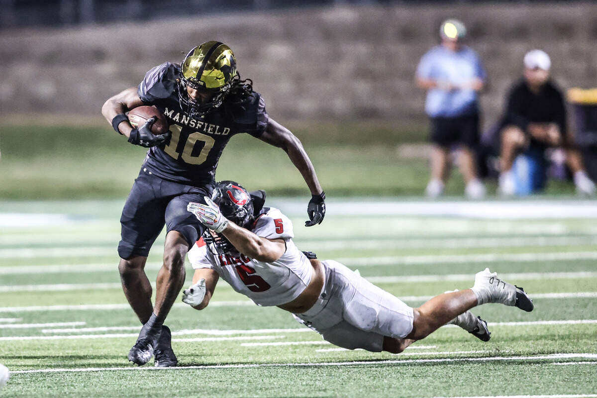 Mansfield’s Larry Scruggs gets pulled down by Legacy’s Carson Cox In Friday’s game at Vernon Newsom Stadium. Special to the Star-Telegram / Tom Marvin