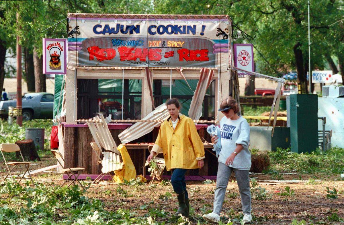 The day after the hail storm, Mayfest volunteers Charlotte Cummings and Judy Bohnsack walk past a damaged food booth in Trinity Park. May 6, 1995.