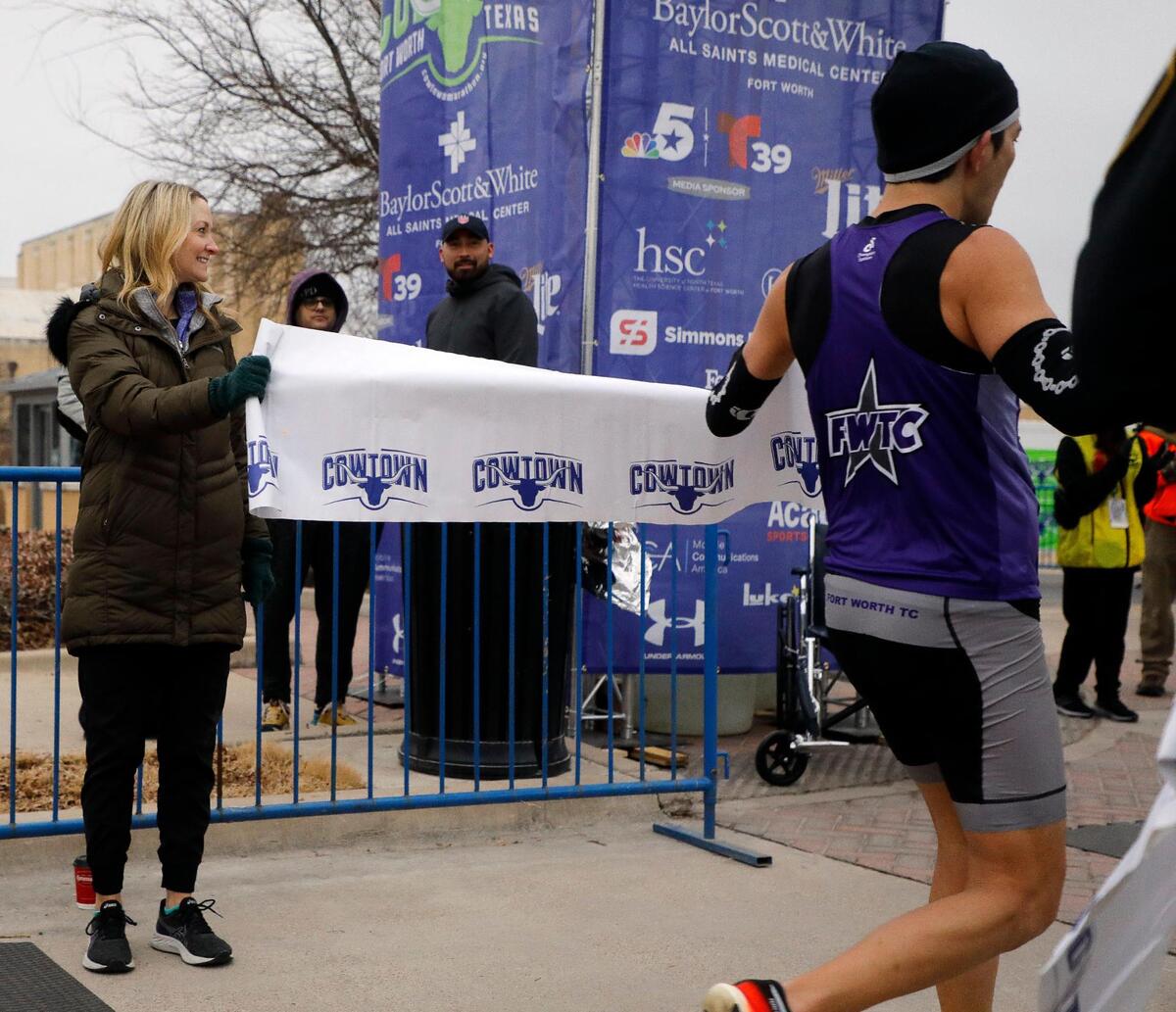Fort Worth Mayor Mattie Parker holds the 10K banner as Keith Kotar crosses the finish line during the 44th annual running of The Cowtown at Will Rogers Memorial Center in Fort Worth, Texas, Saturday, Feb. 26, 2022. 
