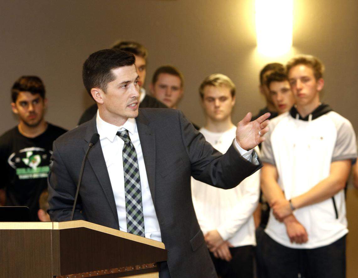 With Dragon football players in the background, Riley Dodge is introduced as the new head coach during a Carroll school board meeting March 26, 2018.