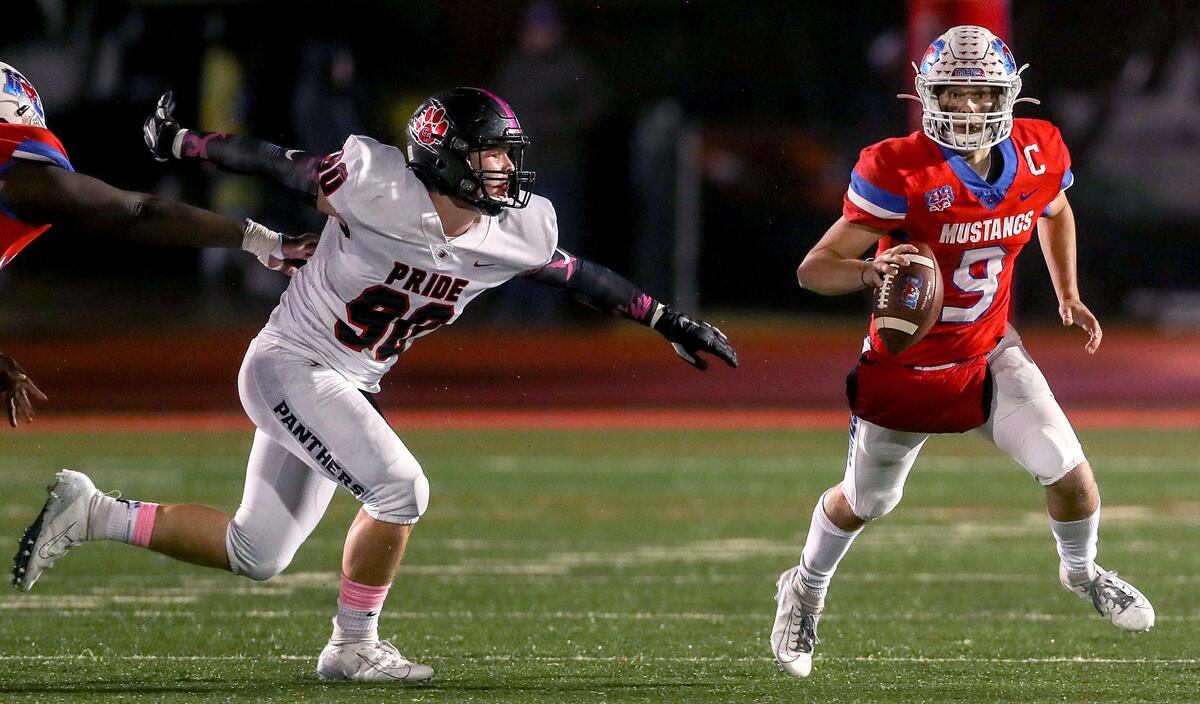 Grapevine quarterback Austin Alexander (9) tries to scramble away from Colleyville Heritage defensive lineman Taylor Steele (90) during the first haif, Friday night, October 25, 2019 played at Mustang-Panther Stadium in Grapevine, TX.