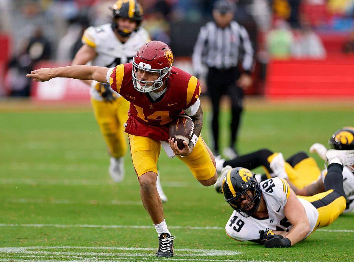 LOS ANGELES, CALIFORNIA - NOVEMBER 15: Jayden Maiava #14 of the Southern California Trojans avoids a tackle from Ethan Hurkett #49 of the Iowa Hawkeyes during the first half at Los Angeles Memorial Coliseum on November 15, 2025 in Los Angeles, California. (Photo by Harry How/Getty Images)