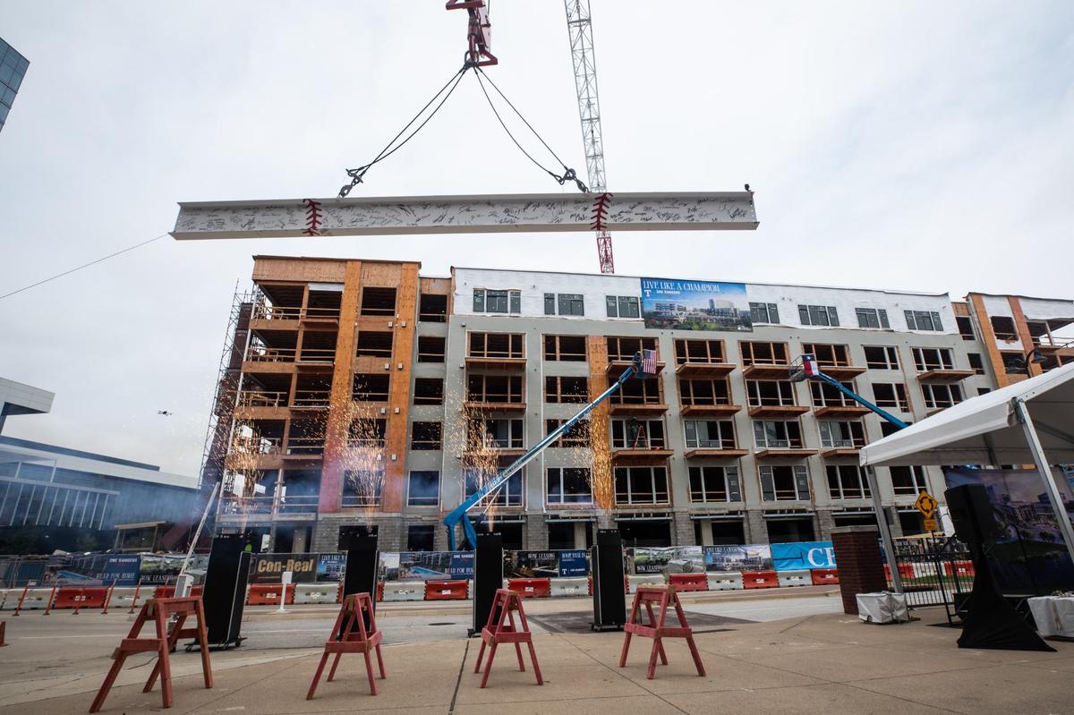 A beam rises into the air to be placed on the building during the topping off ceremony on Monday for the new One Rangers Way luxury apartments in Arlington’s entertainment district.