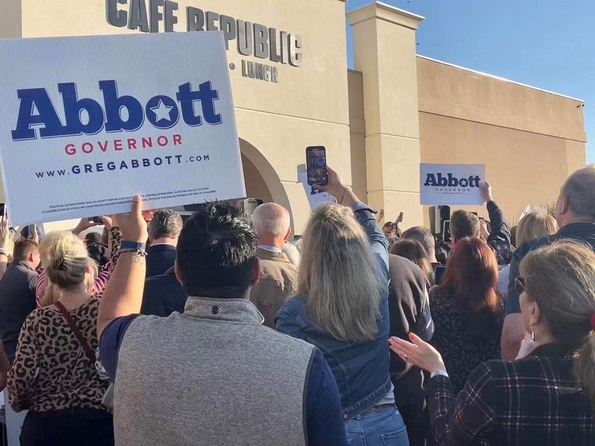 People attending a Greg Abbott campaign event hold up signs supporting Abbott outside of Cafe Republic in far north Fort Worth. 