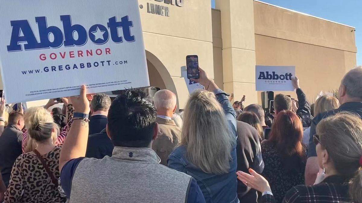 People attending a Greg Abbott campaign event hold up signs supporting Abbott outside of Cafe Republic in far north Fort Worth. 