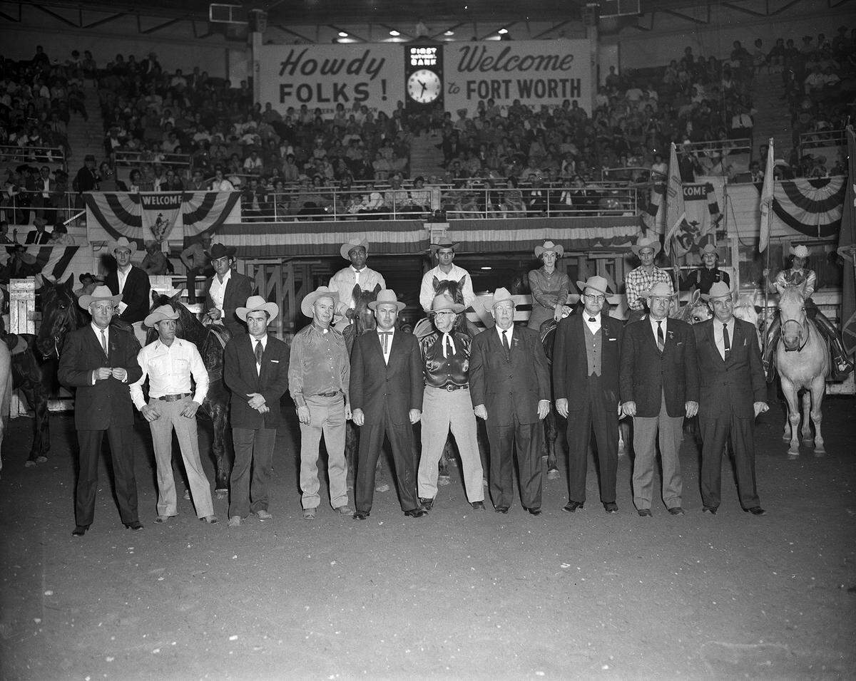 Fort Worth Stock Show officials pose with the champions at the final performance and closing ceremonies of the 1962 Stock Show rodeo. On horses are the champions, who include Ernest “Buddy” Bramwell (top row, third from left) of Marlow, Oklahoma, the first place winner in steer wrestling. 