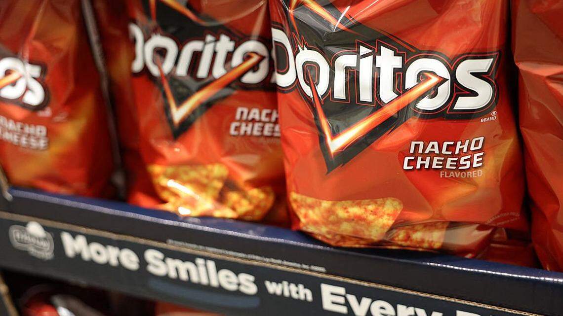 Bags of PepsiCo's Frito-Lay Doritos nacho cheese tortilla chips are displayed alongside packaged foods for sale at a warehouse grocery store in Hawthorne, California.