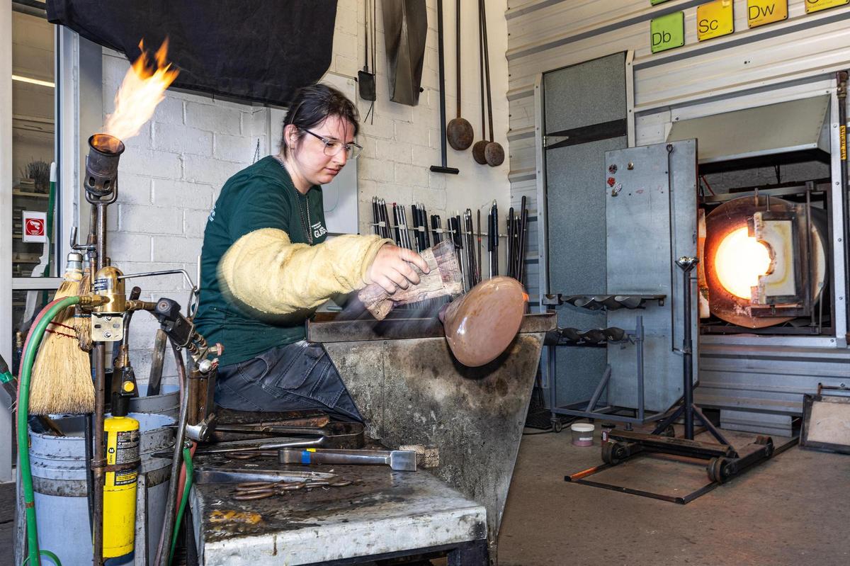 Isabella Raquel Posca, a University of Texas Arlington Glass student, works on molding the molten glass into an open vase during the Arts Goggle event on Magnolia Avenue in Fort Worth on Saturday, Oct. 19, 2024.