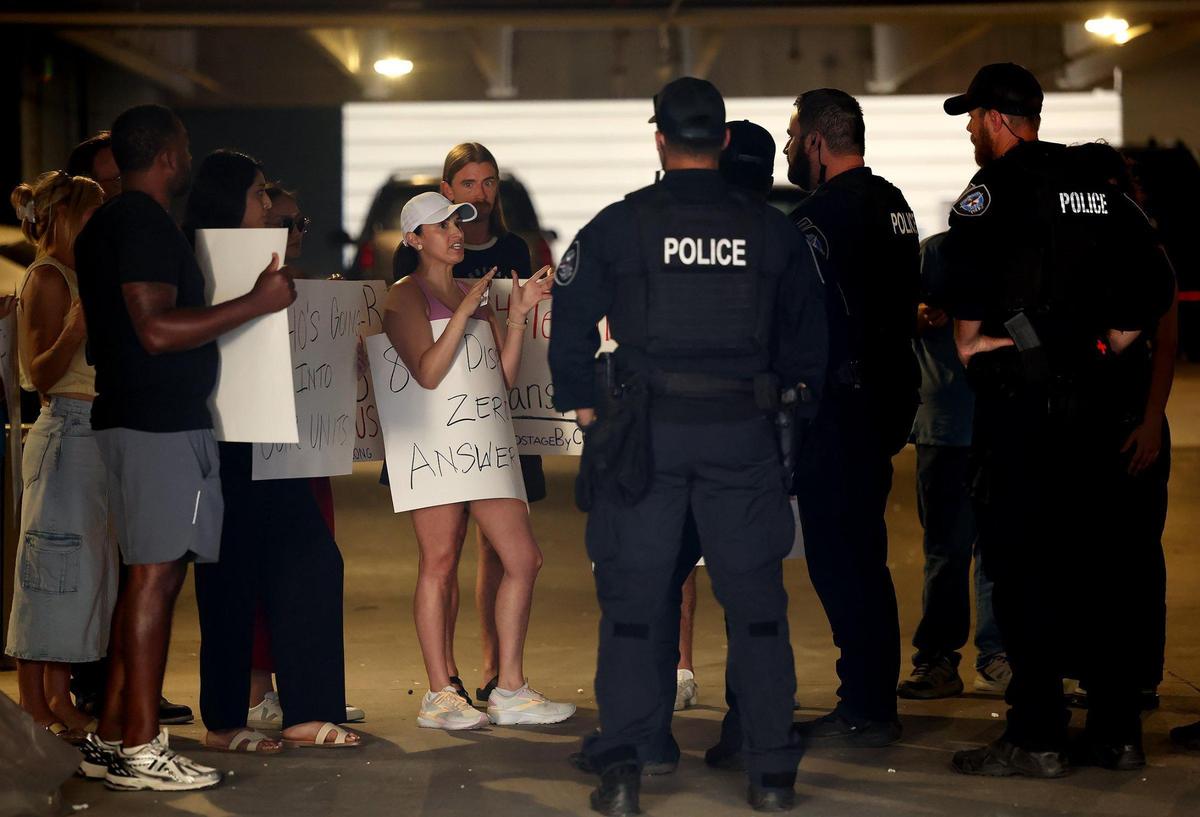 Residents of The Cooper protesting a lack of communication from the owners of the complex explain their grievances to members of the Fort Worth Police Department after refusing to leave the parking garage until speaking with management on Monday, July 7, 2025. They said there has been little to no information given to them following a six-alarm fire that closed the building.
