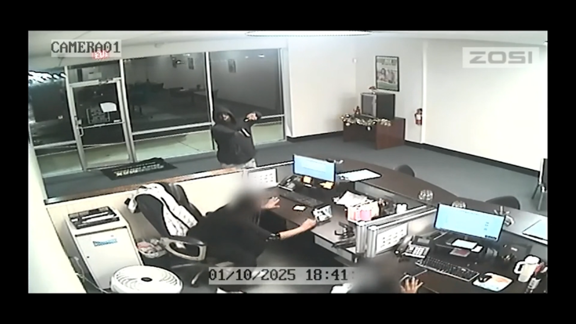 One of the suspects in the Jan. 10, 2025, robbery of a CashMax store in Arlington points a gun at employees in this image from video released by police. The robbers bound the employees’ arms and legs with tape, investigators said. Officers exchanged gunfire with one of the suspects, but no one was injured, according to police.