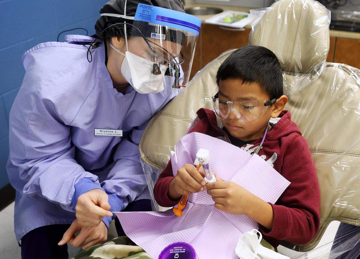 Bryanna Lytle, a second year dental hygiene student at Tarrant Community College, shows Angel Lopez, 7, how long he should brush his teeth at a clinic in November. The TCC dental hygiene department partnered with Save a Smile to provide 19 children with no-cost preventive oral care.