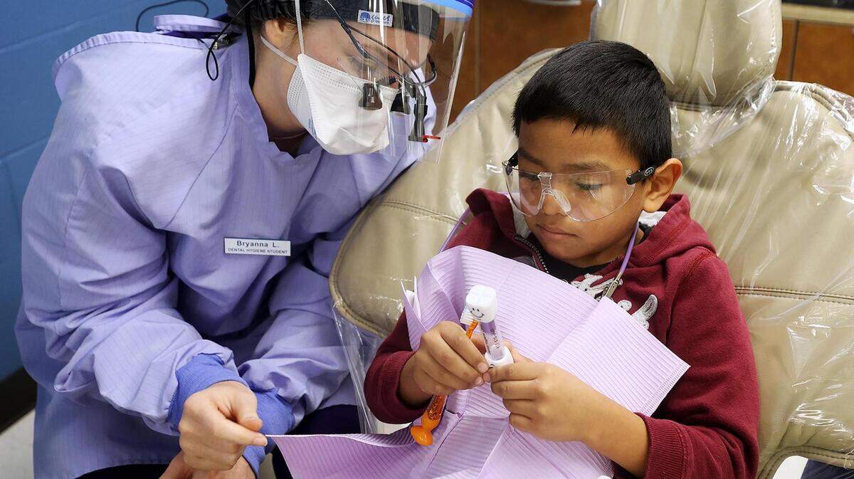 Bryanna Lytle, a second year dental hygiene student at Tarrant Community College, shows Angel Lopez, 7, how long he should brush his teeth on Friday, November 12, 2021. Gov. Newsom’s proposed $144M cut to Medi-Cal Dental threatens children’s access to care; lawmakers must preserve progress in pediatric oral health.