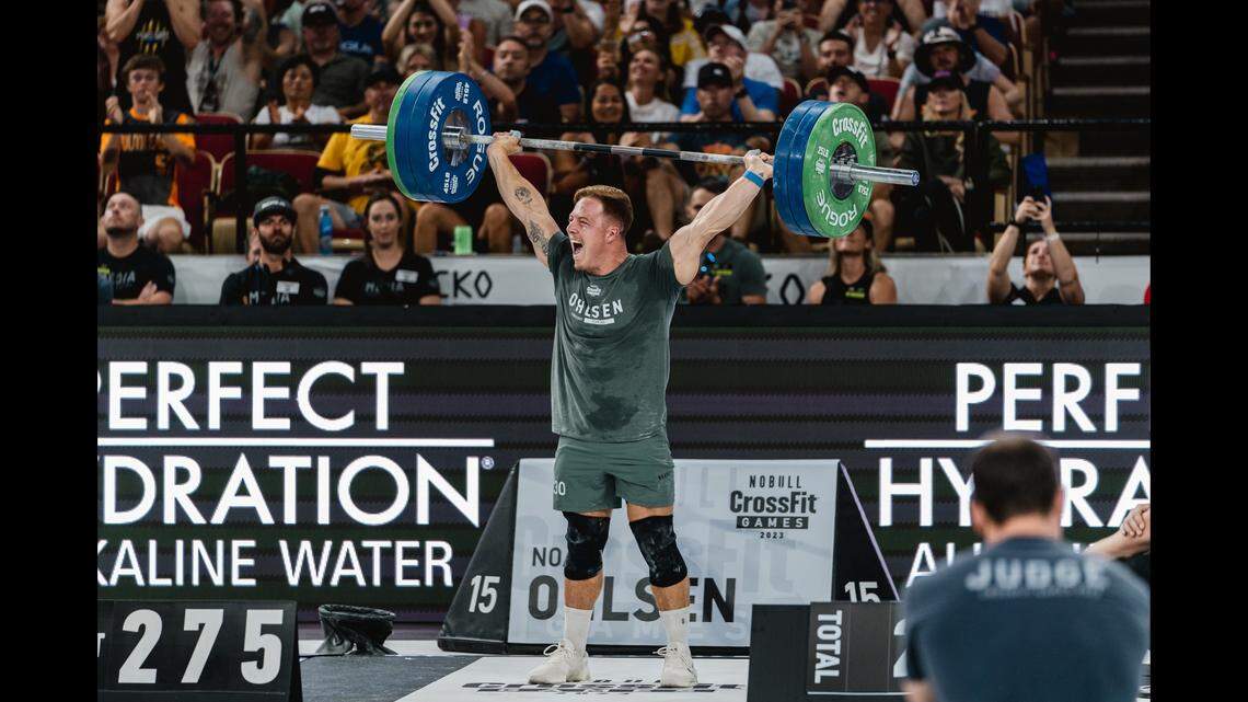 A man dead lifting 275 pounds over his head at a competition