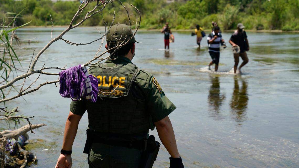 A Border Patrol agent watches as a group of migrants walk across the Rio Grande on their way to turn themselves in upon crossing the U.S.-Mexico border in Del Rio, Texas, in, 2021. (AP Photo/Eric Gay, File)