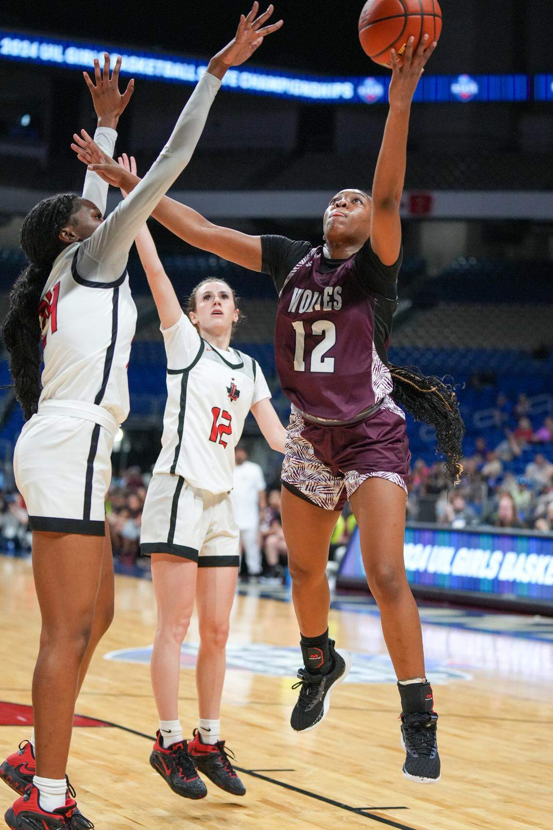 Mansfield Timberview’s Chrishawn Coleman (12 in maroon) goes up between Frisco Liberty’s Aaliyah Williams (24) and Kathryn Murphy (12 in white) in the Class 5A state championship game on Saturday, March 2, 2024 at the Alamodome in San Antonio, Texas. Liberty defeated Timberview 60-51.