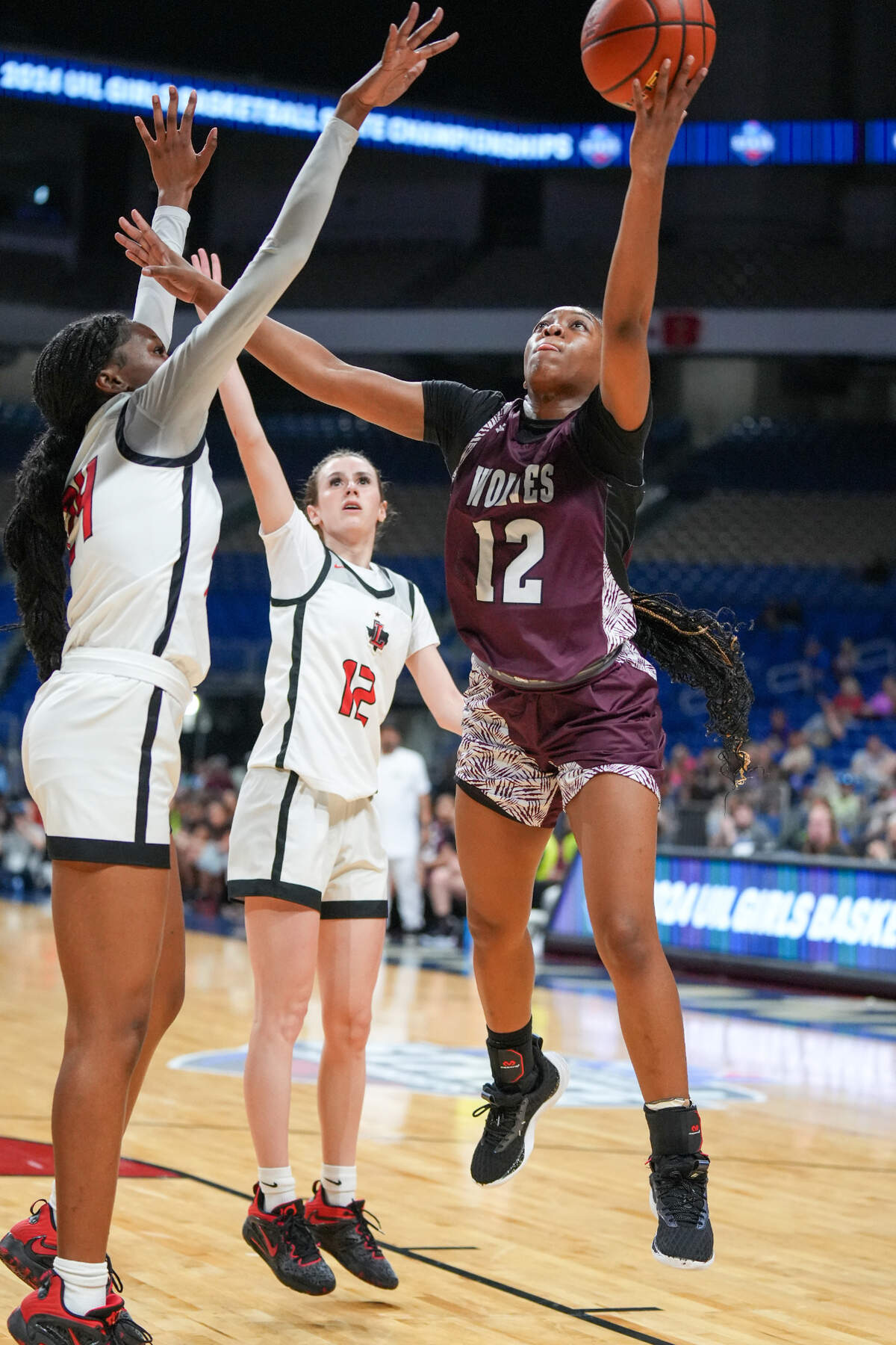 Mansfield Timberview’s Chrishawn Coleman (12 in maroon) goes up between Frisco Liberty’s Aaliyah Williams (24) and Kathryn Murphy (12 in white) in the Class 5A state championship game on Saturday, March 2, 2024 at the Alamodome in San Antonio, Texas. Liberty defeated Timberview 60-51.
