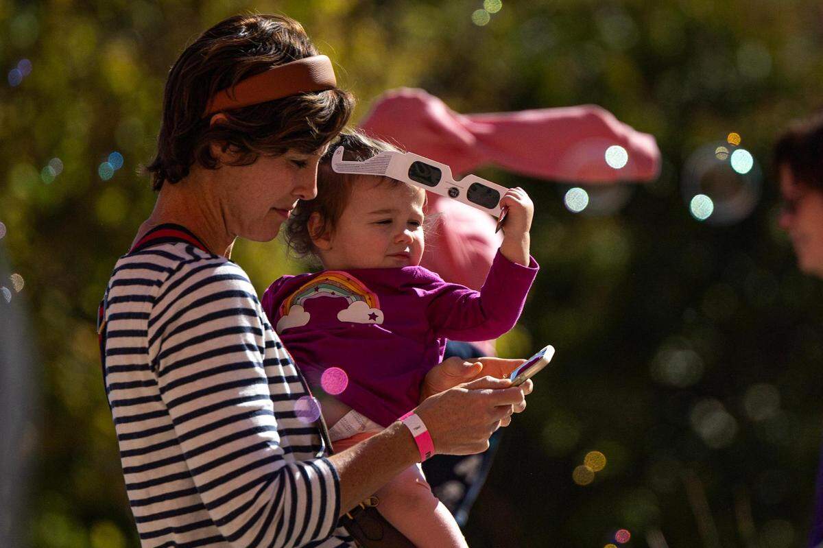 Maryann Means-Dufrene carries her daughter Margot, 1, during the Annular Solar Eclipse event at the Fort Worth Museum of Science & History on Saturday, Oct. 14, 2023.
