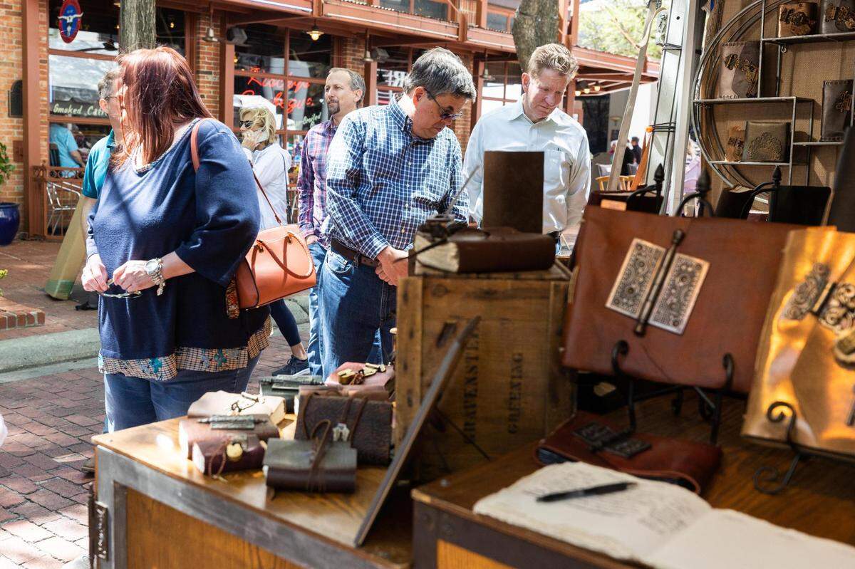 Festival goers check out art in booths during the Main Street Fort Worth Arts Festival Thursday, April 7, 2022, in downtown Fort Worth.