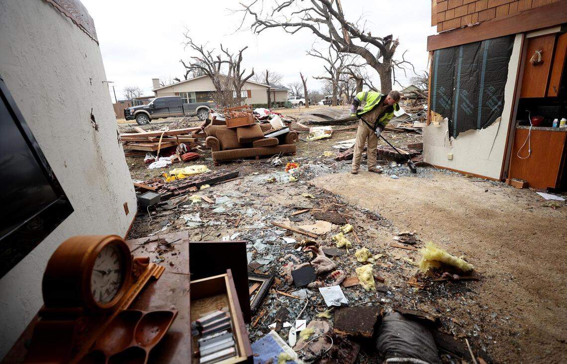 Nathan Flury of Dallas helps to clean debris and glass from Frances Wilson’s Jacksboro home on March 22.