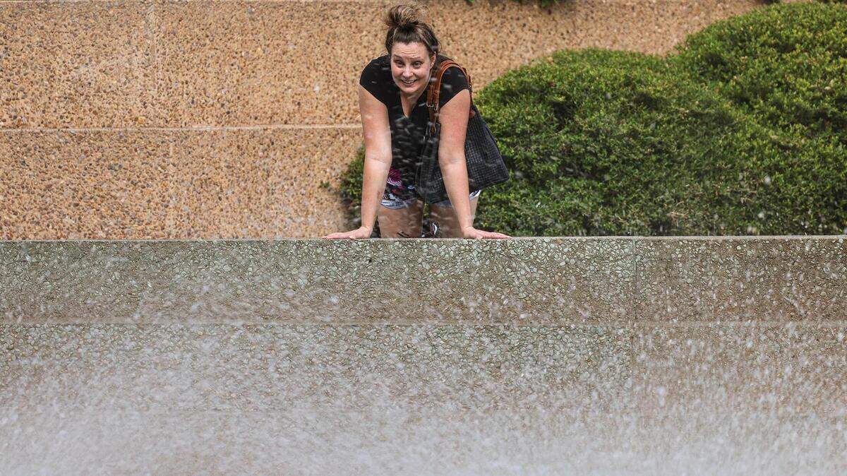 Woman leans over fountain spraying water