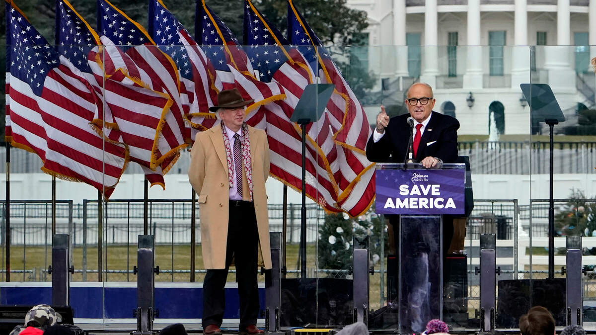Former Chapman University law professor John Eastman stands at left as former New York Mayor Rudolph Giuliani speaks during former President Donald Trump’s “Save America Rally” in Washington on Jan. 6, 2021. Eastman also spoke at the rally and helped devise Trump’s conspiracy of a rigged election and attempt to stop Congress from certifying the election that day, according to the bipartisan Jan. 6 Committee investigation.