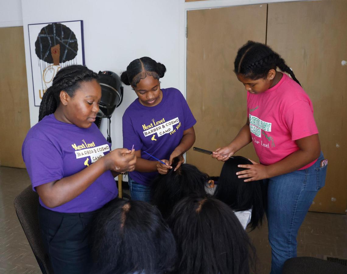 D’Asia Jones, 12, Serenity Brown, 11, and Kayniah Williams, 11, work on their wigs at Next Level Barber and Cosmo camp.