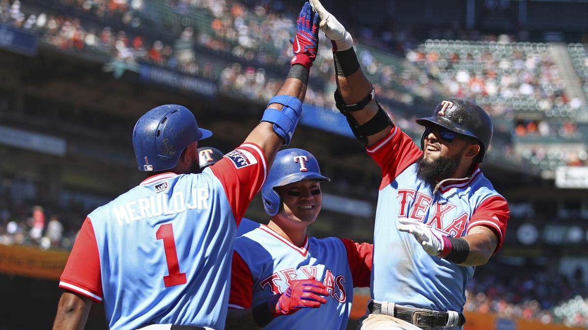 Elvis Andrus and Shin-Soo Choo celebrate with Rougned Odor after he connected for a three-run homer in the eighth inning Saturday. Odor was 1 for 17 to open the road trip before collecting three hits Saturday.