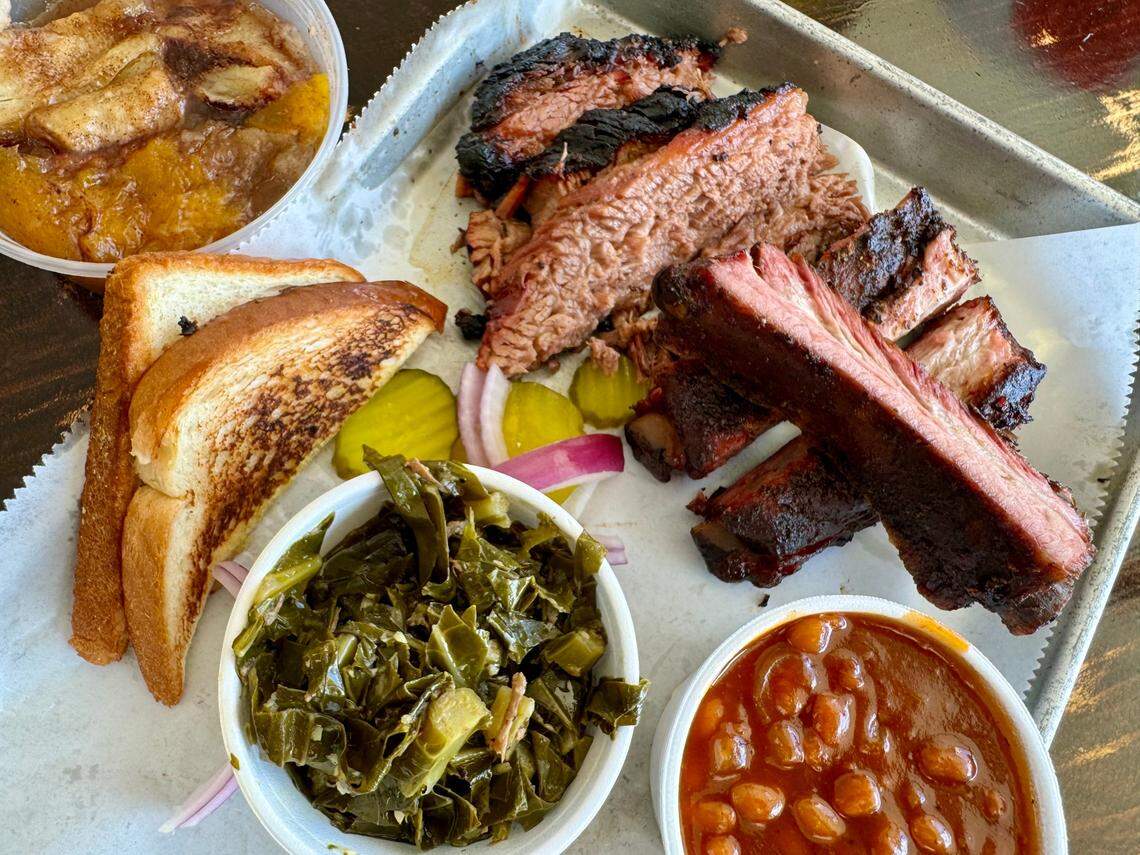 A traditional barbecue plate with brisket, ribs, collard greens and peach cobbler at Smoke‘N Ash BBQ in Arlington.