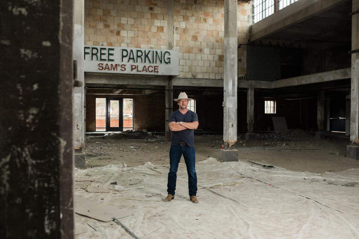 Chef Tim Love standing, arms crossed, in a vacant building located in the Stockyards.
