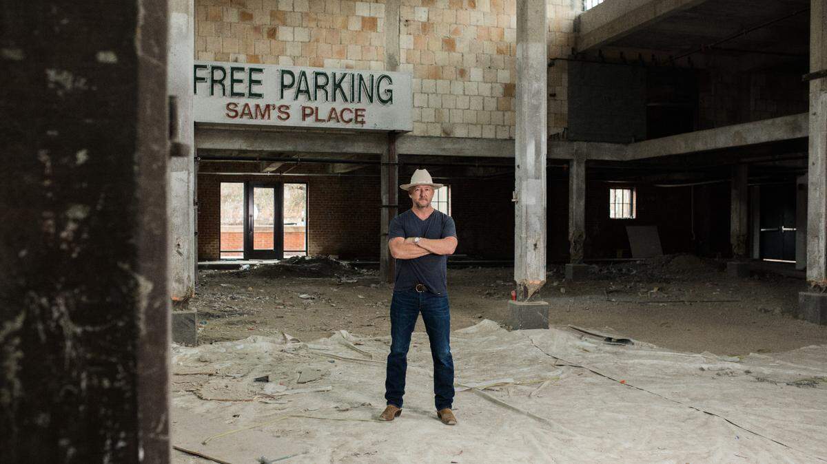 Chef Tim Love standing, arms crossed, in a vacant building located in the Stockyards.