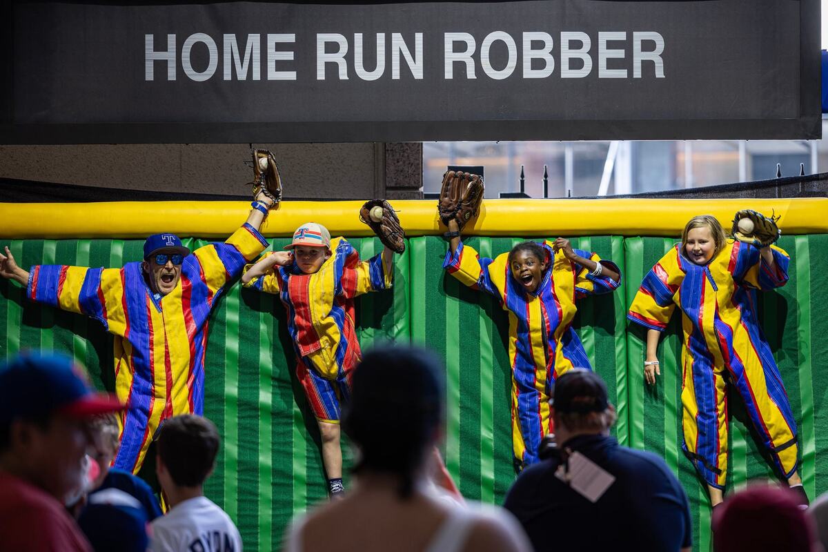 Brad Holdbrook, left, and his children Turner, 7, Allie, 10, and Hadley, 9, participate in the Home Run Robber photo on the first day of the 2024 MLB All-Star Village at Choctaw Stadium in Arlington on Saturday, July 13, 2024.