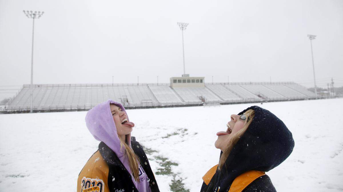 In this file photo from Feb. 11, 2010, Lamar High seniors Claire VanBeber and Hailey Sisson catch snowflakes on their tongues on Cravens Field in Arlington.