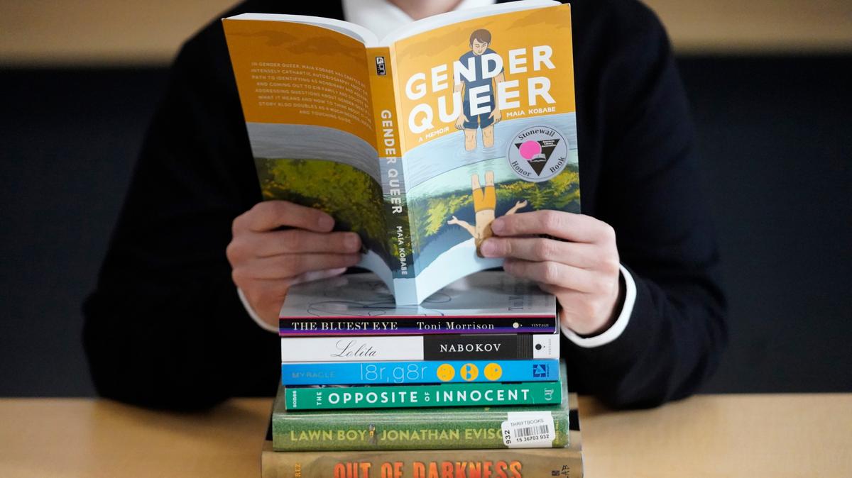 Amanda Darrow, director of youth, family and education programs at the Utah Pride Center, poses with books that have been the subject of complaints from parents on Dec. 16, 2021, in Salt Lake City.