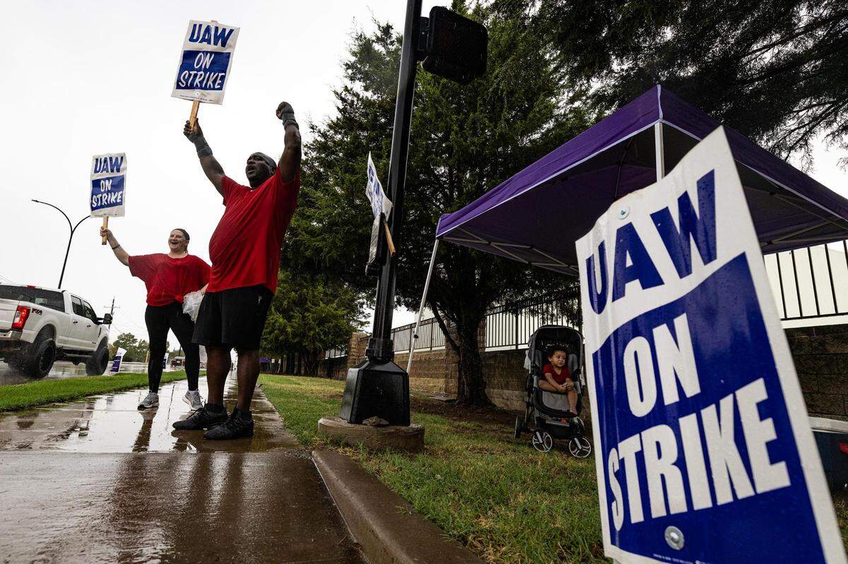 General Motors employee Edward Bartlett is joined by his wife Trista, left, and their 19-month-old son Auhsten on strike outside of the General Motors Assembly Plant in Arlington on Tuesday, Oct. 24, 2023. Bartlett is a temporary employee at the assembly plant and said he isn’t making enough to support his family. “When I am making $16 an hour and the person next to me is making $30 an hour doing the same job, it’s just unfair.”
