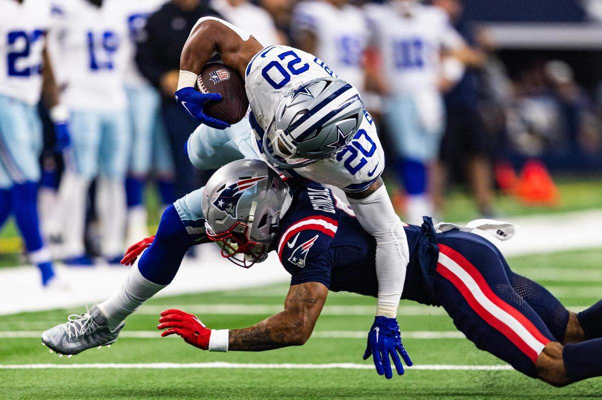 Cowboys running back Tony Pollard (20) gets tackled by Patriots cornerback Christian Gonzalez (6) in the first half of an NFL game between the Dallas Cowboys and New England Patriots at AT&T Stadium in Arlington on Sunday, Oct. 1, 2023.
