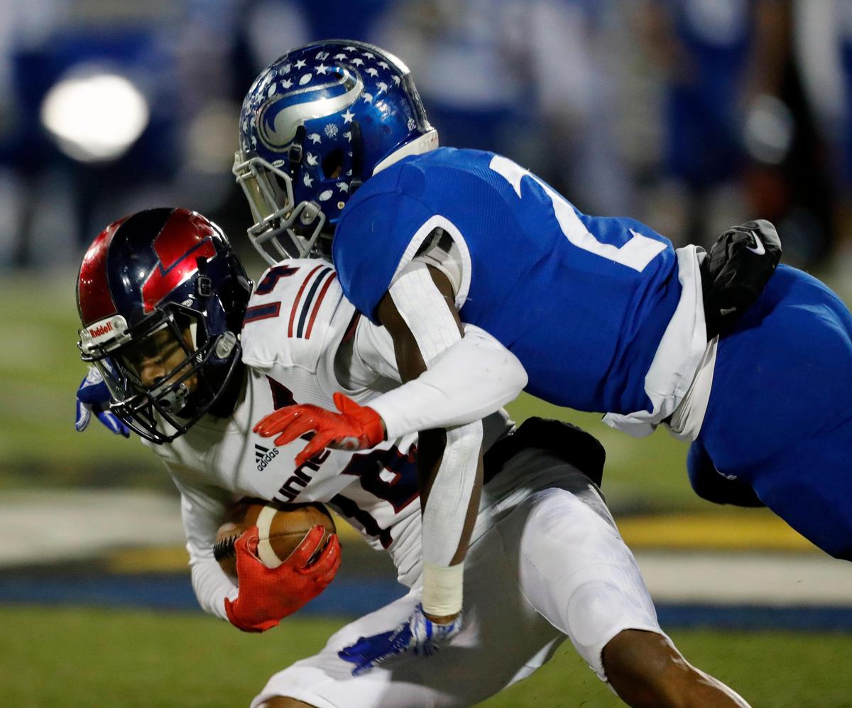 Nolan Catholic cornerback Devin Thomas, right, brings down Bishop Dunne receiver Brian Fleming during the teams’ playoff game Saturday, Nov. 16 at Doskocil Stadiuim in Fort Worth. Thomas is one of six former YMLA football players who are contributing for the Vikings after their former school dropped the sport in 2018.