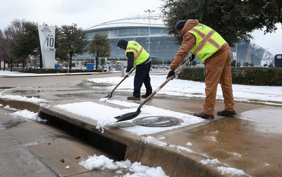 City of Arlington employees Terrence Smith, left, and Daniel Warnick clear the sidewalk on East Randol Mill Road outside of AT&T Stadium on Friday, Jan. 10, 2025 in Arlington. The Cotton Bowl will kick off at 6:30 p.m.