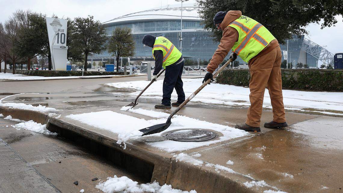 City of Arlington employees Terrence Smith, left, and Daniel Warnick clear the sidewalk on East Randol Mill Road outside of AT&T Stadium on Friday, Jan. 10, 2025 in Arlington. The Cotton Bowl will kick off at 6:30 p.m.