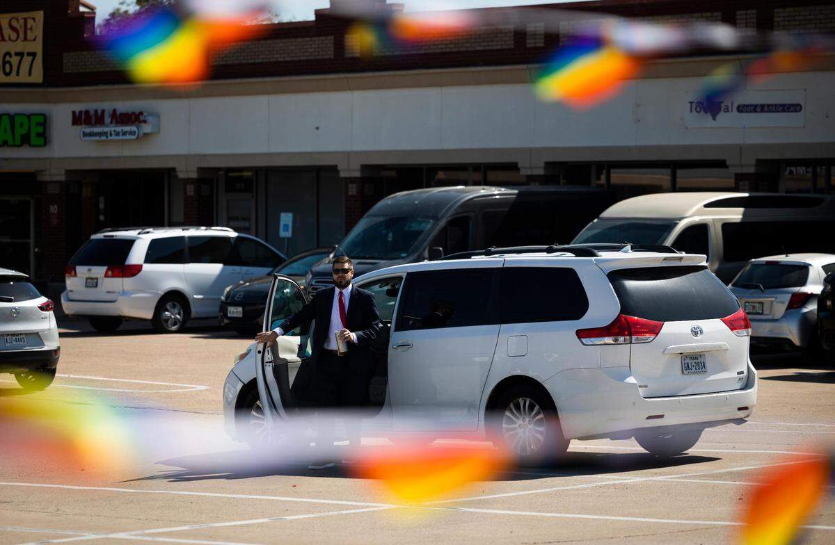 Pride flags stream in from the No Hate in Texas protest as Jonathan Shelley, leader of Stedfast Baptist Church, exits a vehicle in the parking lot outside the church on July 24 in Watauga. Previously, Shelley had said he is following teachings from the Bible and he is not advocating for violence against homosexuals.