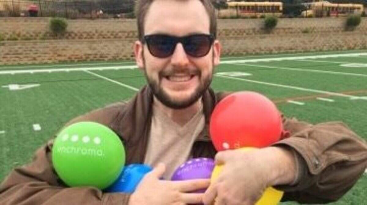 TCU alum Drew Curd poses with the balloons he can finally see, thanks to his new glasses that can correct his colorblindness.