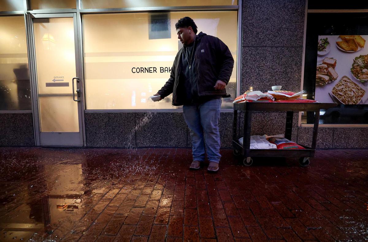 Victor Hernandez sprinkles salt on the sidewalks around the Courtyard Marriott on Thursday, Jan. 9, 2025, in downtown Fort Worth. A winter storm warning is in effect for North Texas.