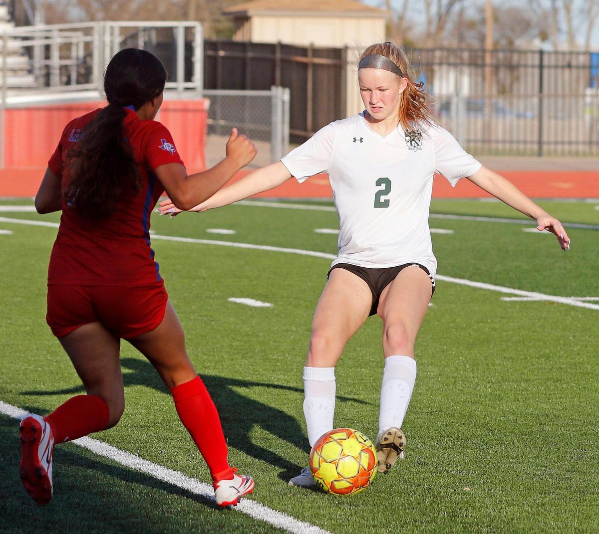 Kennedale’s Cassidy Hughes (2) kicks the ball away from Carter Riverside’s Celeste Alvarez (23) during a 4A Region 1 bi-district girls soccer playoff game at Elk Stadium in Burleson, Texas, Friday, Mar. 25, 2022. Kennedale moves on after defeating Carter Riverside 5-1. (Special to the Star-Telegram Bob Booth)