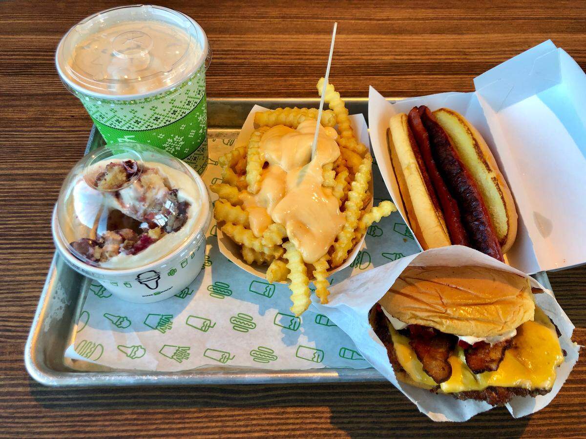 A Shake Shack feast: a Smoke Shack bacon cheesburger with smoked cherry peppers, a hot dog, crinkle fries with cheese sauce, a shake and a custard concrete with Emporium Pies’ Very Berry Pie from Dallas.