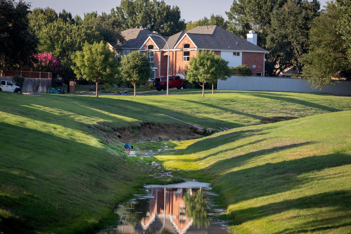 A young Park Glen resident plays in an irrigation channel in the neighborhood in Fort Worth, Texas, on Tuesday, March 13, 2022.